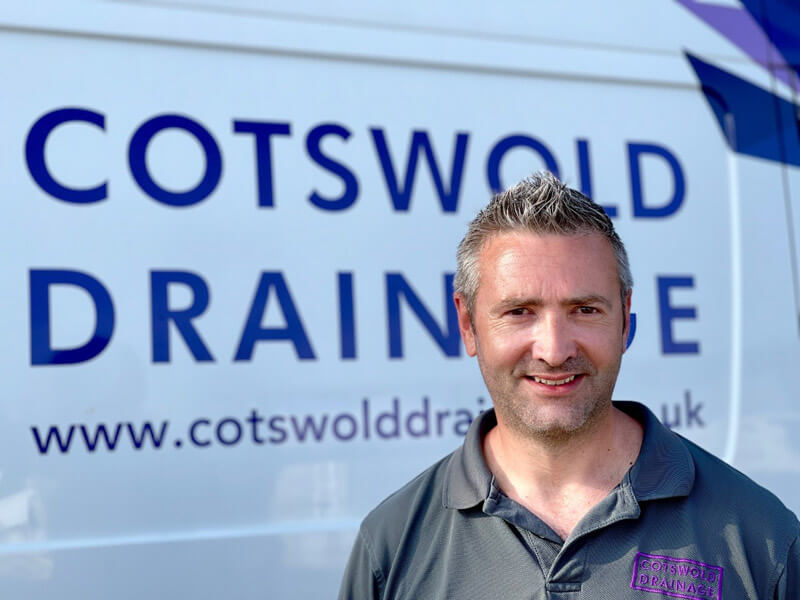 Close-up of a drain unblocking engineer in front of a Cotswold Drainage van